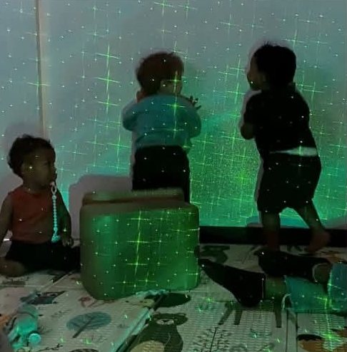Trois enfants découvrent les lumières vertes de la salle Snoezelen