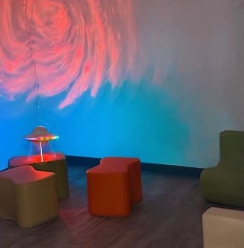 La salle Snoezelen : lumières douces bleues et rouges, poufs colorés